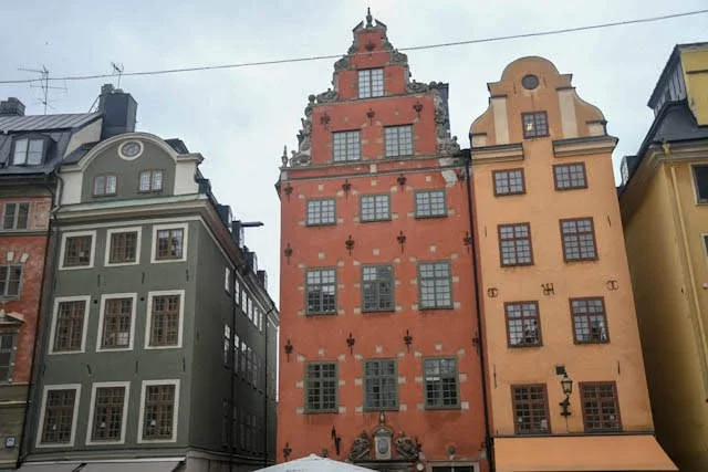 Colorful historic buildings lining a street in a European city, featuring diverse architectural styles and vibrant facades.
