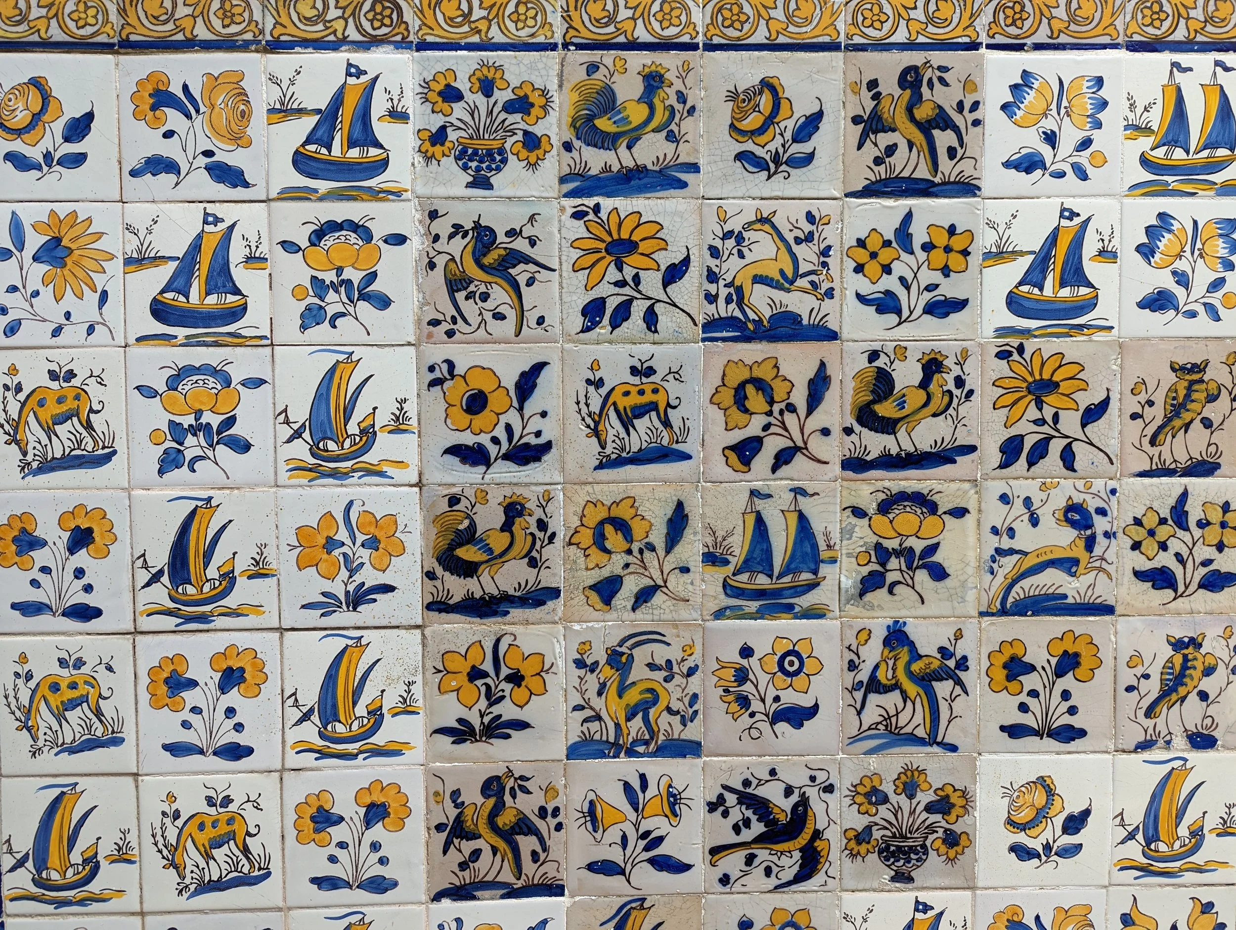 Decorative azulejo tiles featuring ships, birds, flowers, and various abstract patterns in blue, yellow, and white.