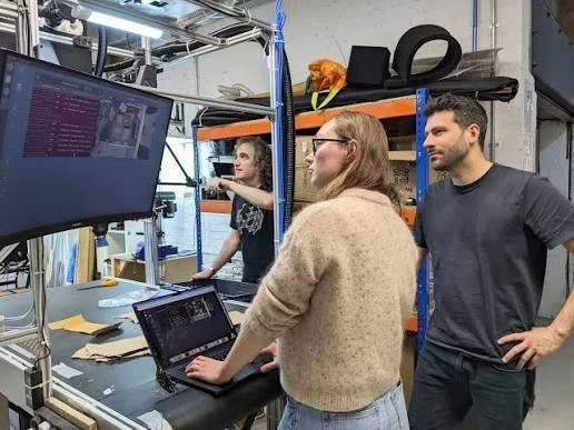 Team reviewing computer screens and equipment in a technology workshop