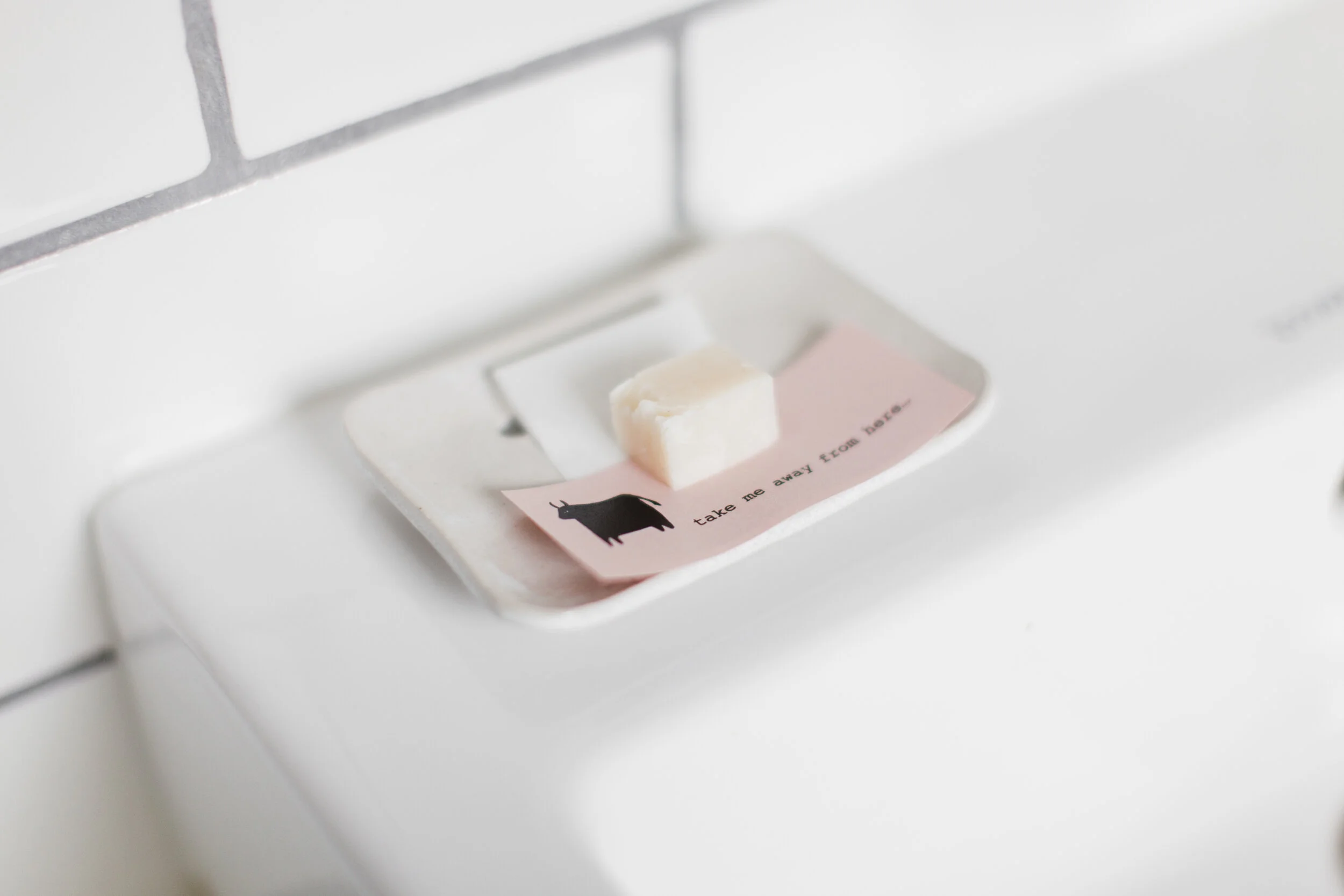 Small soap bar on a tray with a sticky note that features a black bull silhouette and text that says 'take me away from base'.