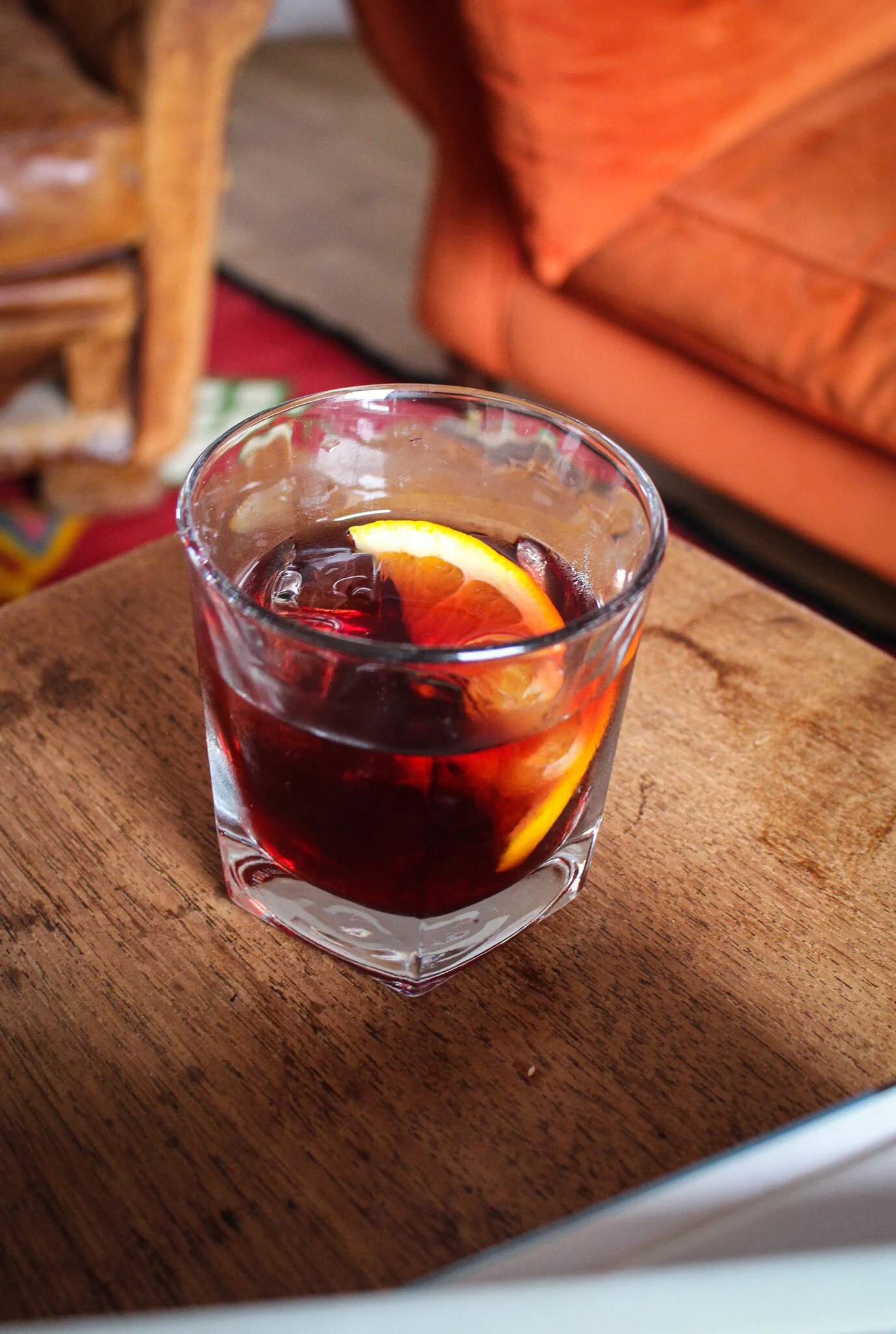 A glass of red beverage with a lemon slice on a wooden table.