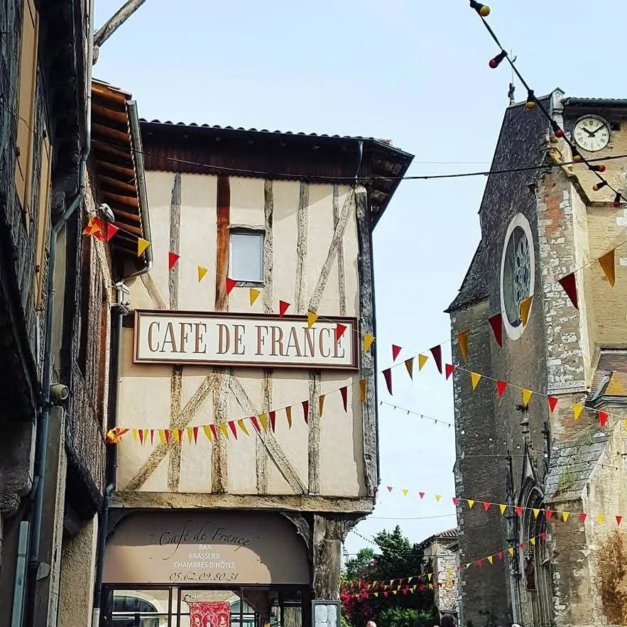 Historic half-timbered French building with the Hôtel de France and a café