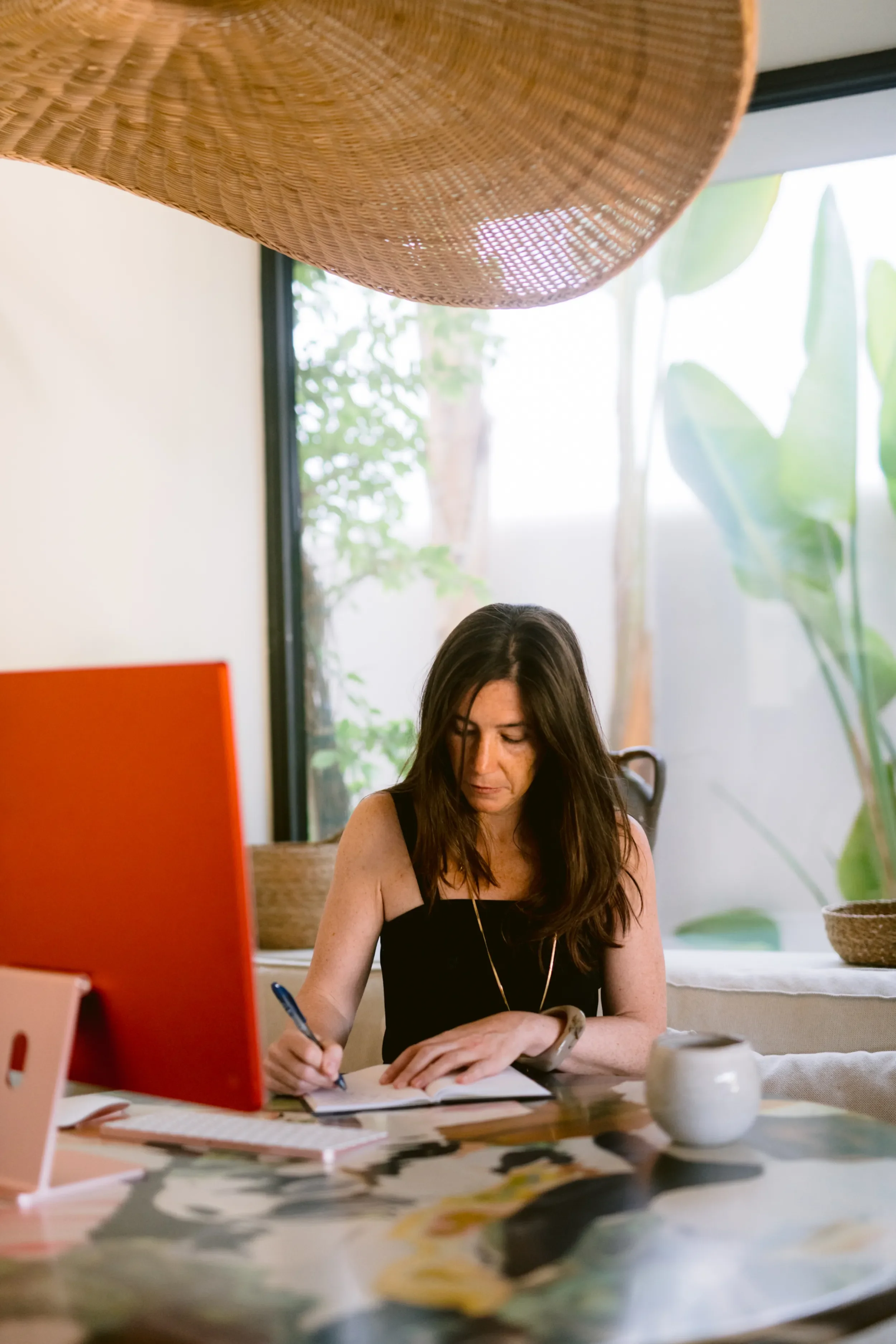 Ana Estrada, executive coach for women, writing notes at her desk while working on Majesta.