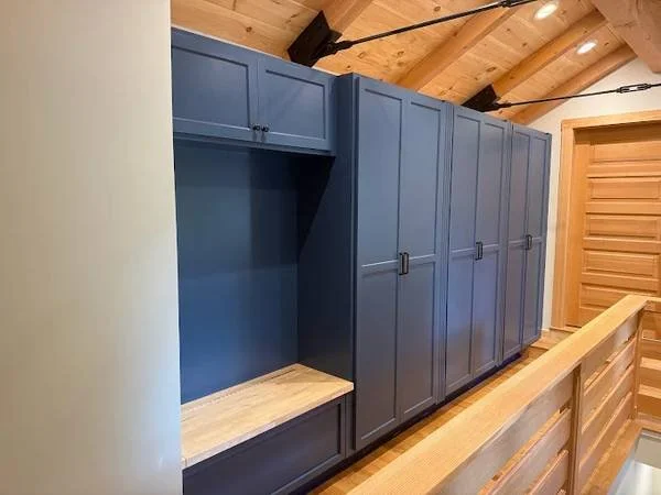 Blue built-in cabinetry with wooden flooring and paneled ceiling in a room with wood accents.