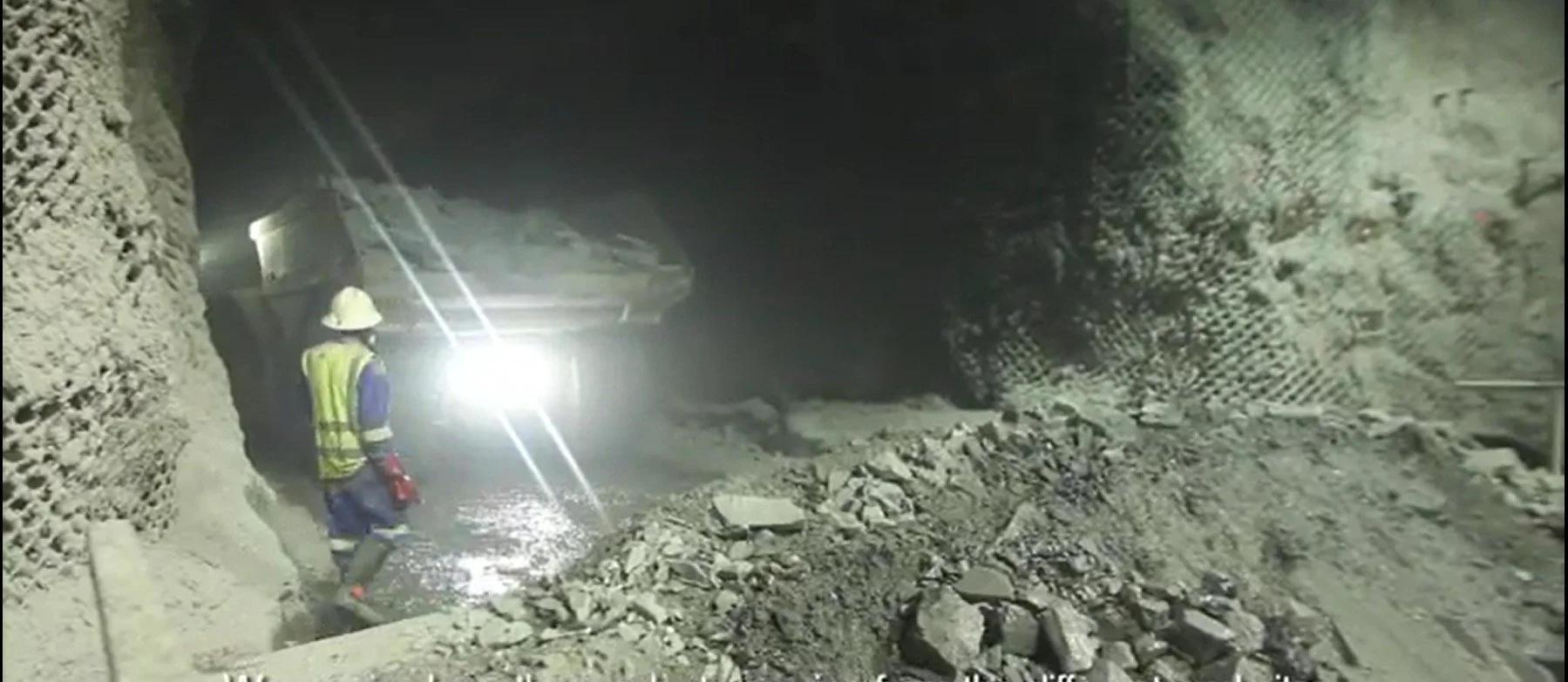 Kamoto underground mine. A miner in safety gear, including a helmet and reflective vest,  illuminated by bright lights.
