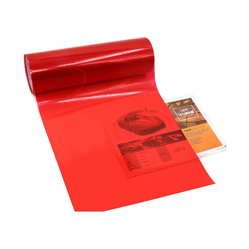 A roll of red sticker film on top of an auto manual of some kind.
