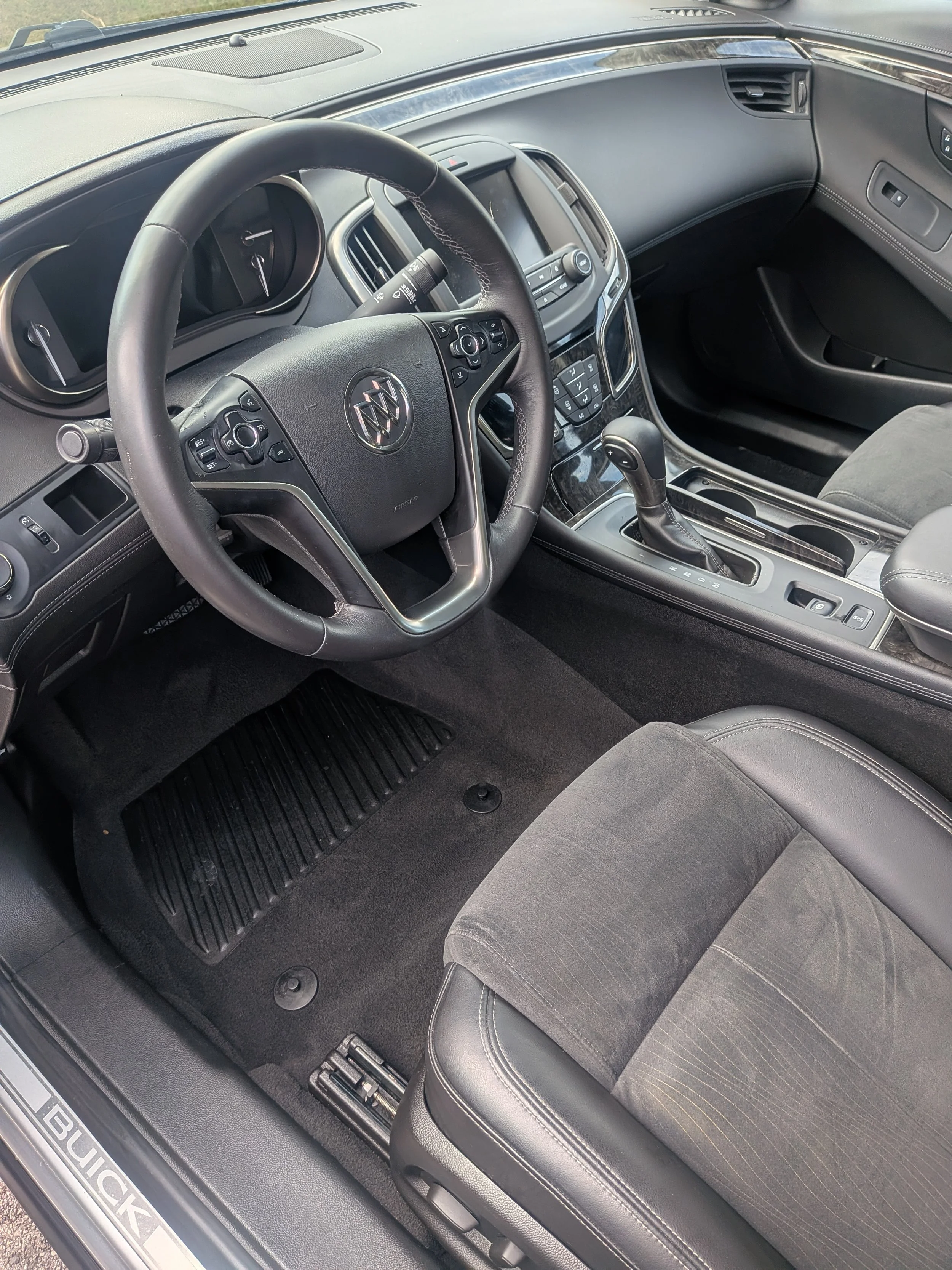 Interior of a Buick vehicle showing the steering wheel, dashboard, center console with gear shift, and front passenger seat.