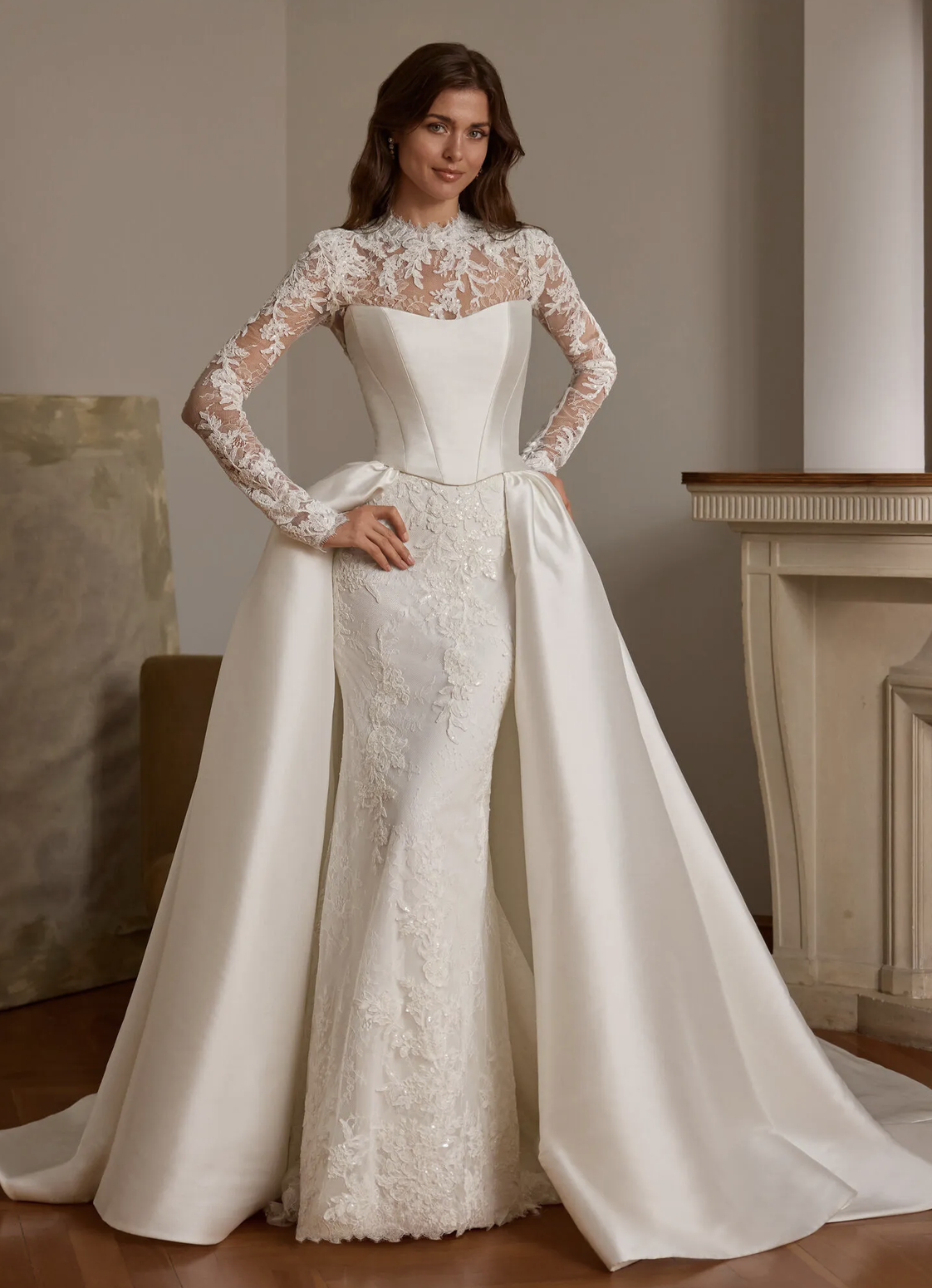 Donna indossa un abito da sposa bianco con gonna a coda e dettagli in pizzo sulla parte superiore, con maniche lunghe in pizzo trasparente.