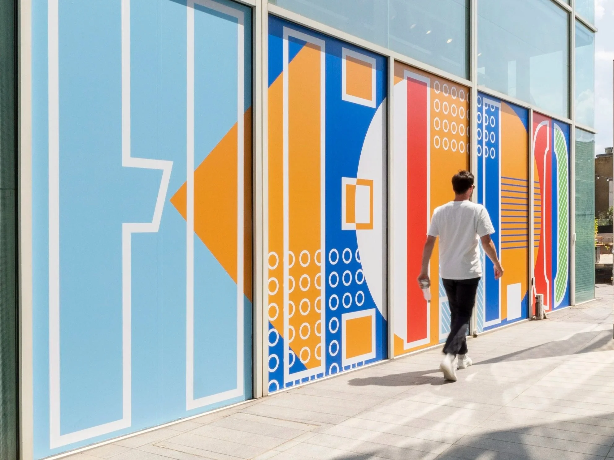 Blue, orange and green geometric graphics applied to full-height windows beside an outdoor office space.