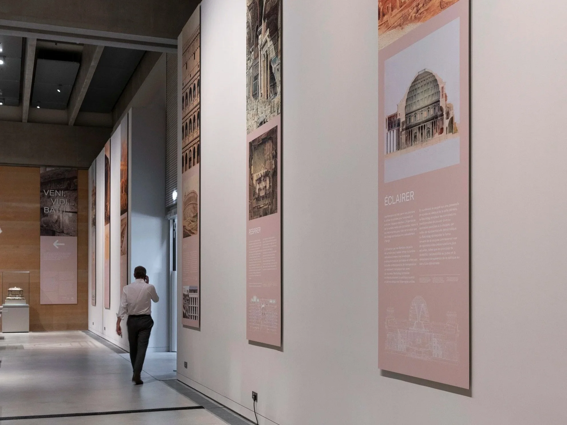 Detail of the vertical panels hanging gtom the ceiling with the intro panel of the exhibition at the end.