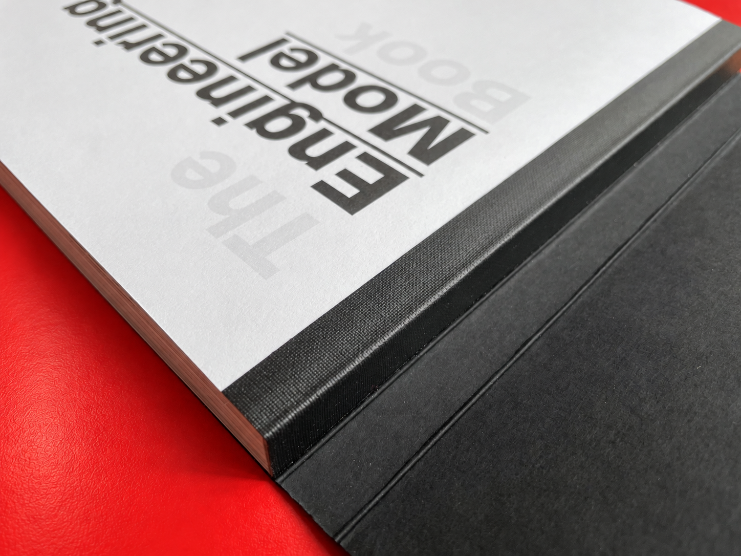 Tape binding detail showing black tape and a close-up of the first page of the book printed in black and white over a red table.