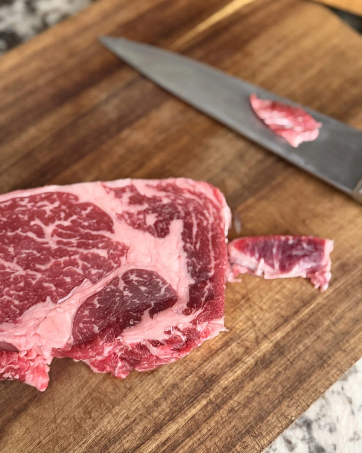 Marbled ribeye with a thin slice on a chef's knife