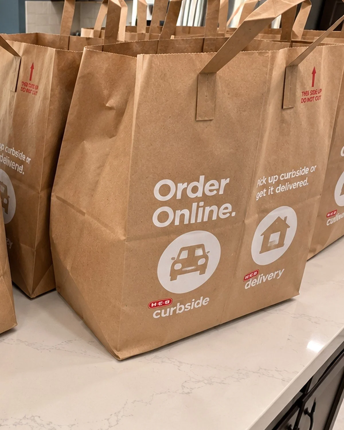 Grocery bags lined up on a white kitchen counter
