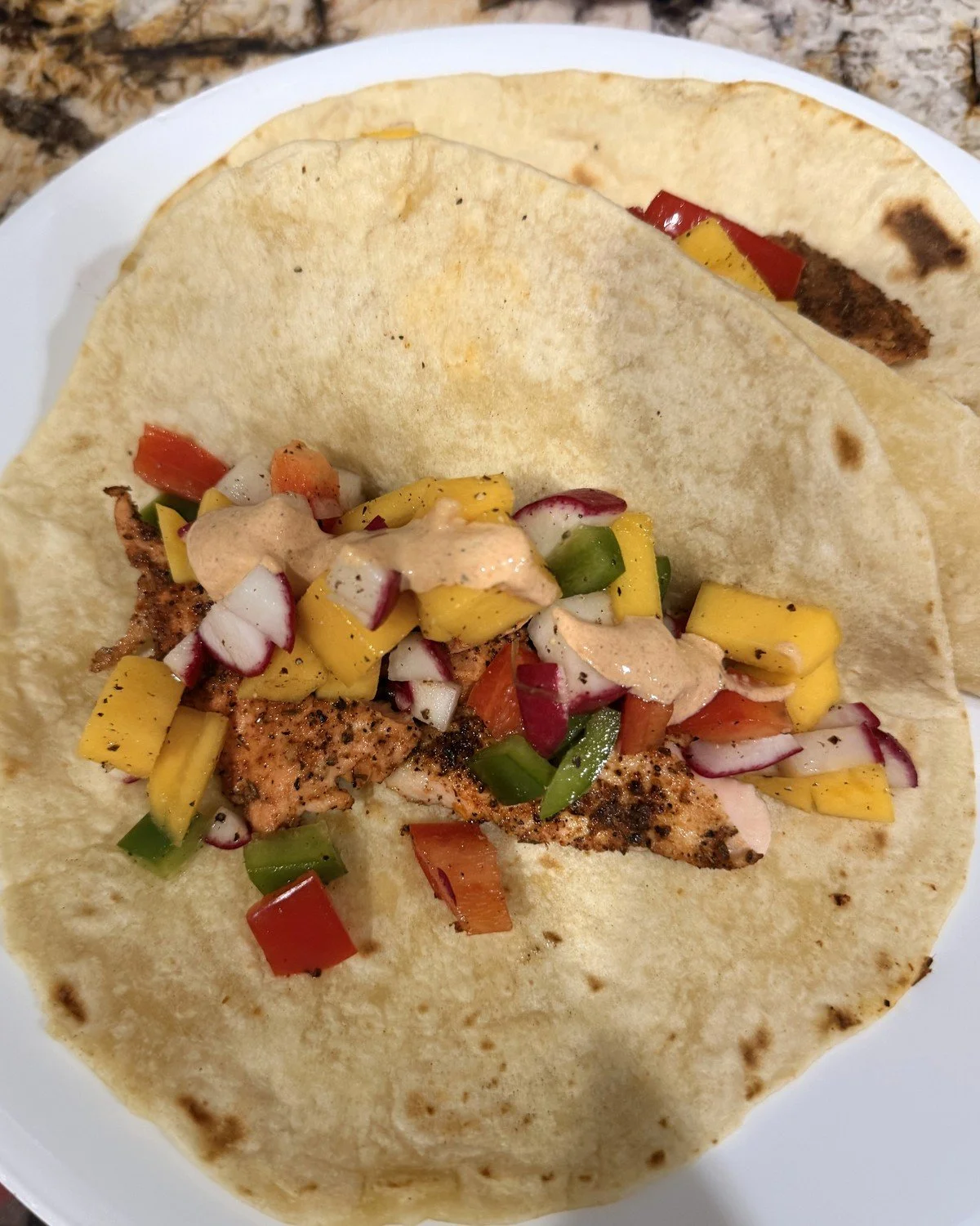 Blackened fish taco with mango-radish salsa and chipotle sauce on a homemade tortilla
