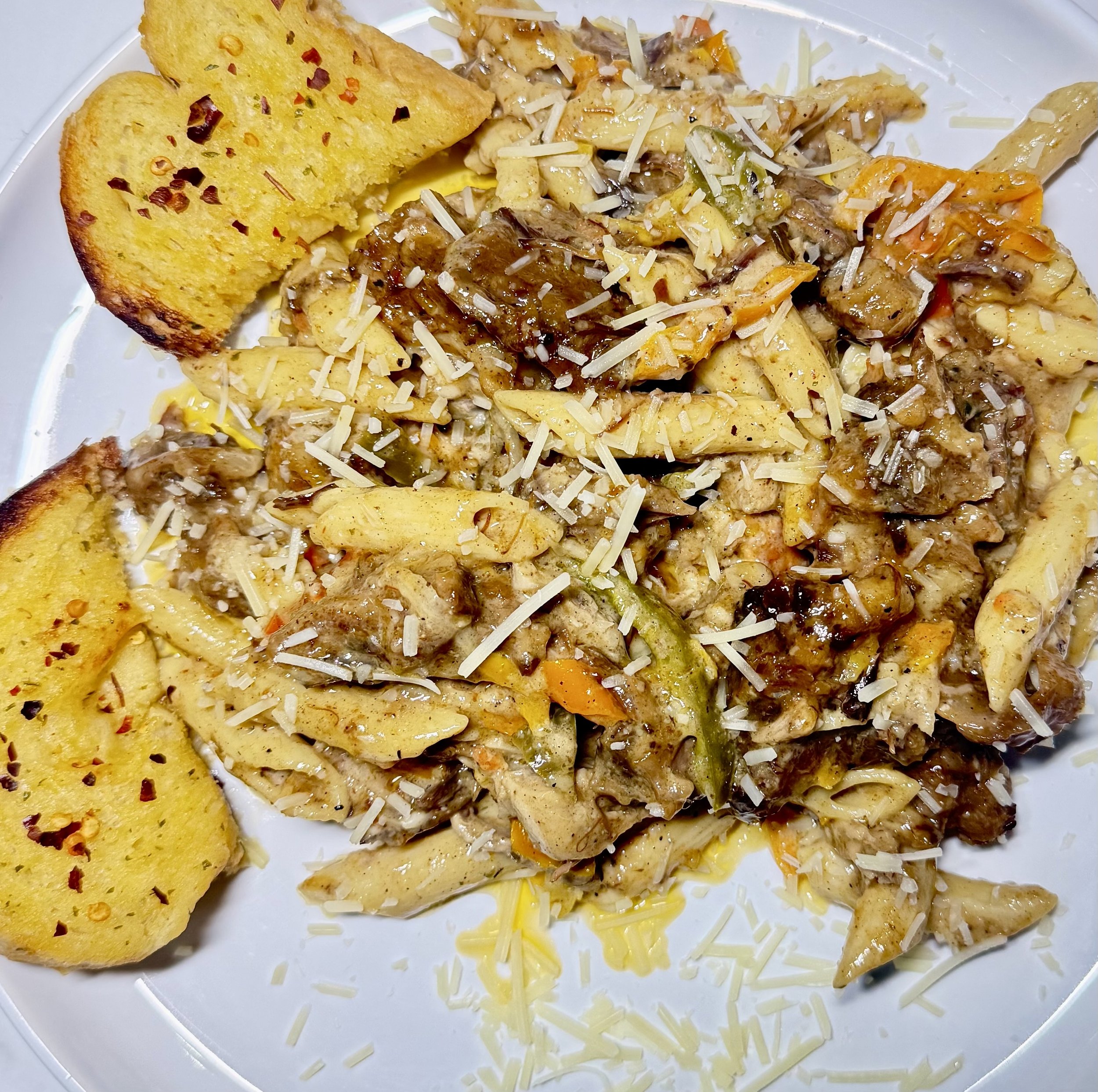 Slices of garlic bread with red pepper flakes on a white plate.