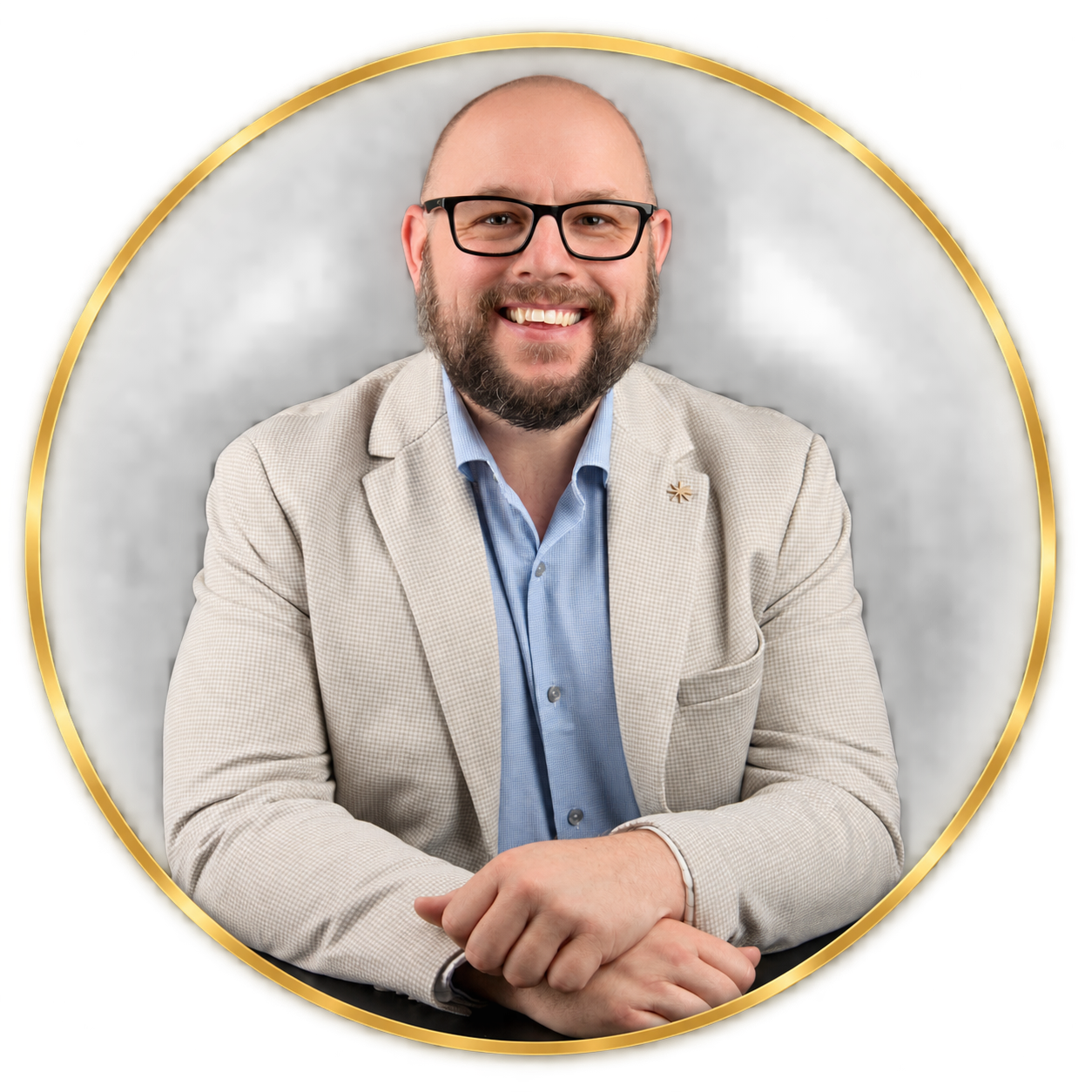 Portrait of a smiling man with glasses, a beard, wearing a light blazer and blue shirt, sitting with his hands folded, surrounded by a gold circular frame.