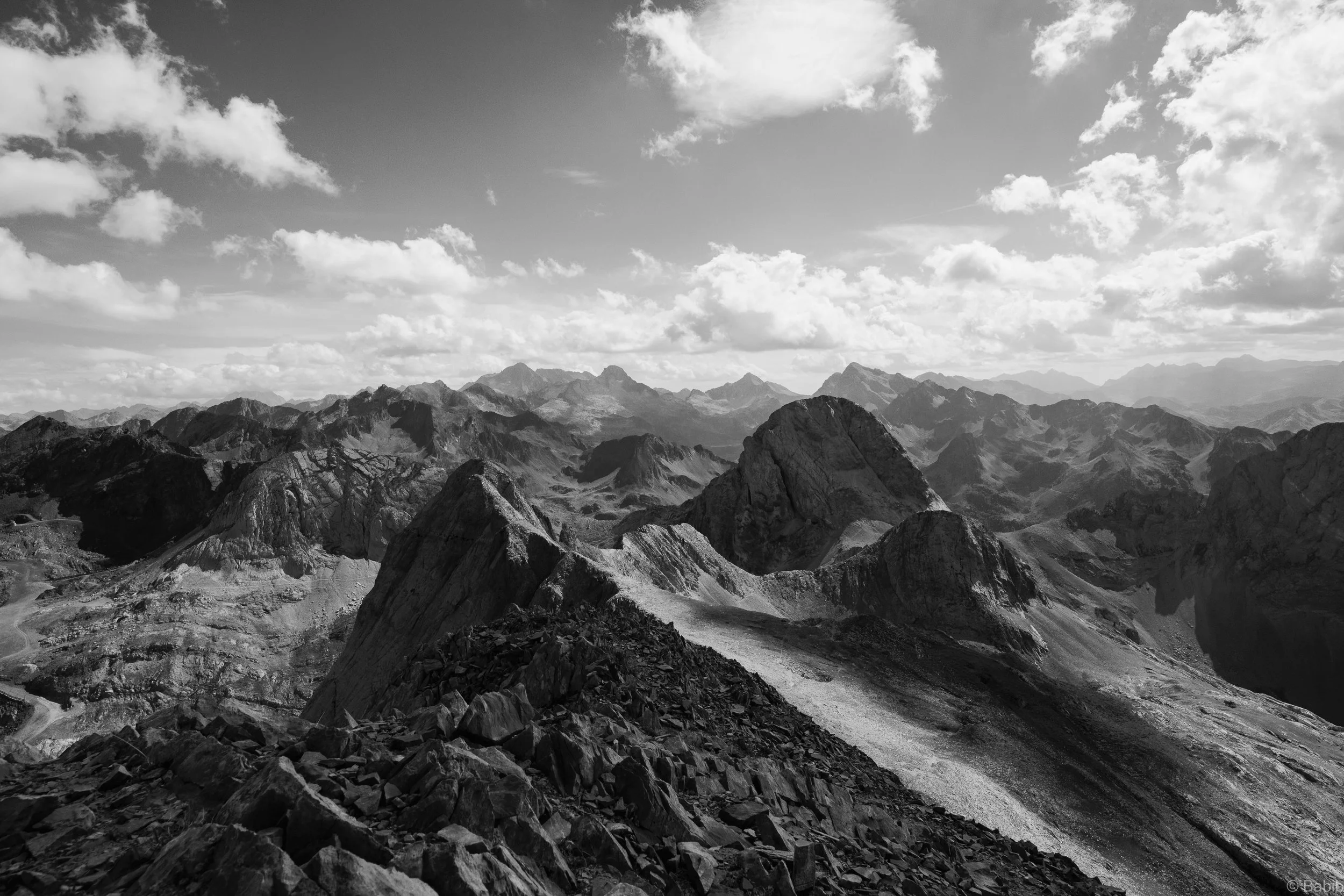 Un paysage de montagnes rocheuses sous un ciel partiellement nuageux.