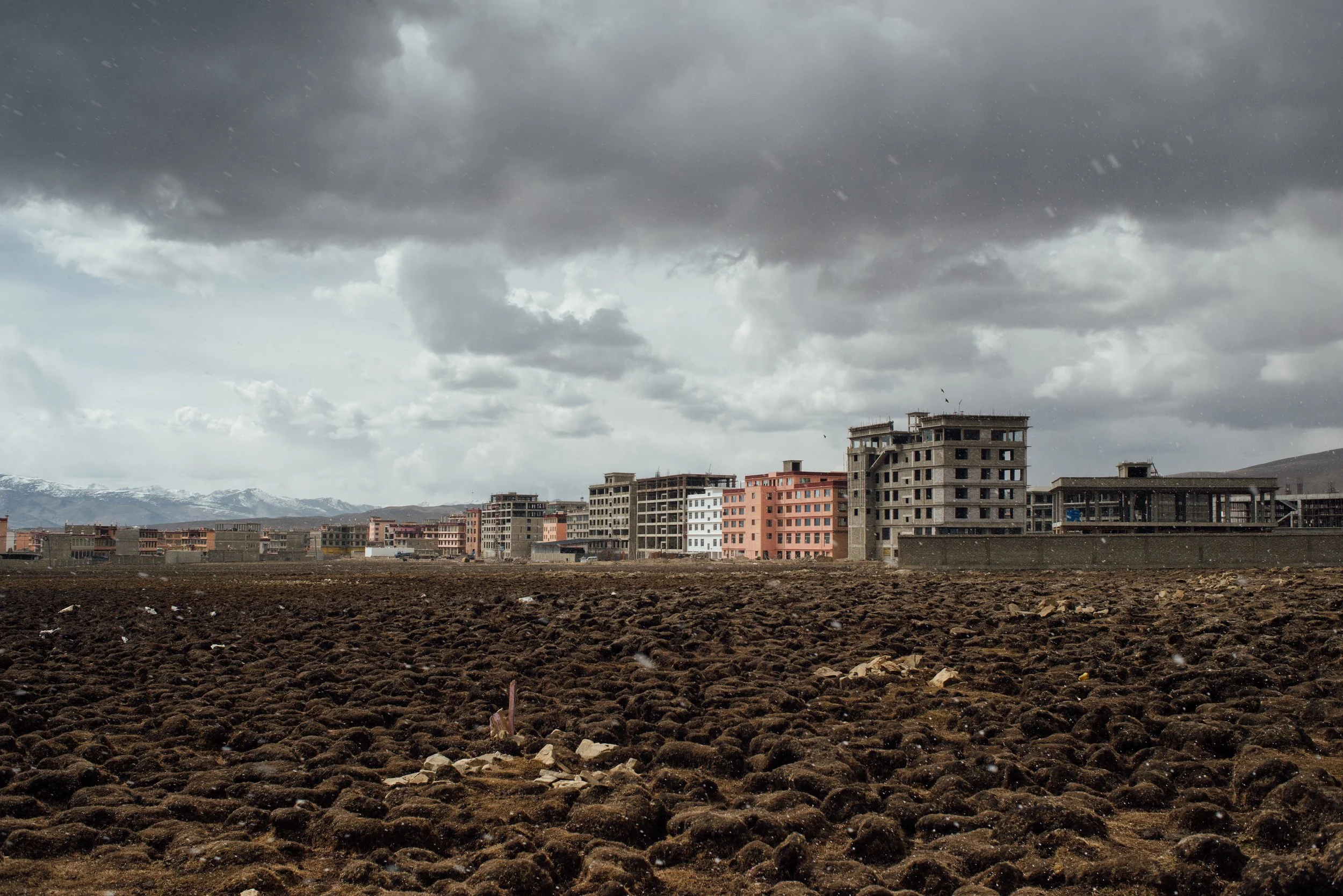 Construction de bâtiments dans une zone urbaine sous un ciel orageux avec des nuages sombres.