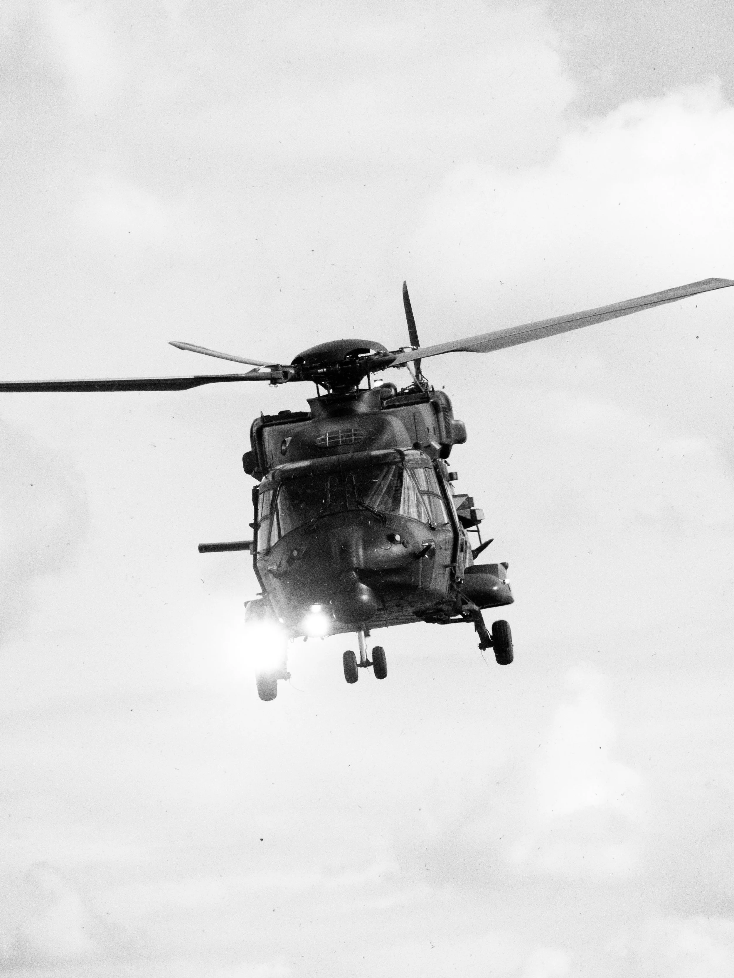 Un hélicoptère en vol, photographié en noir et blanc, venant de dessous.