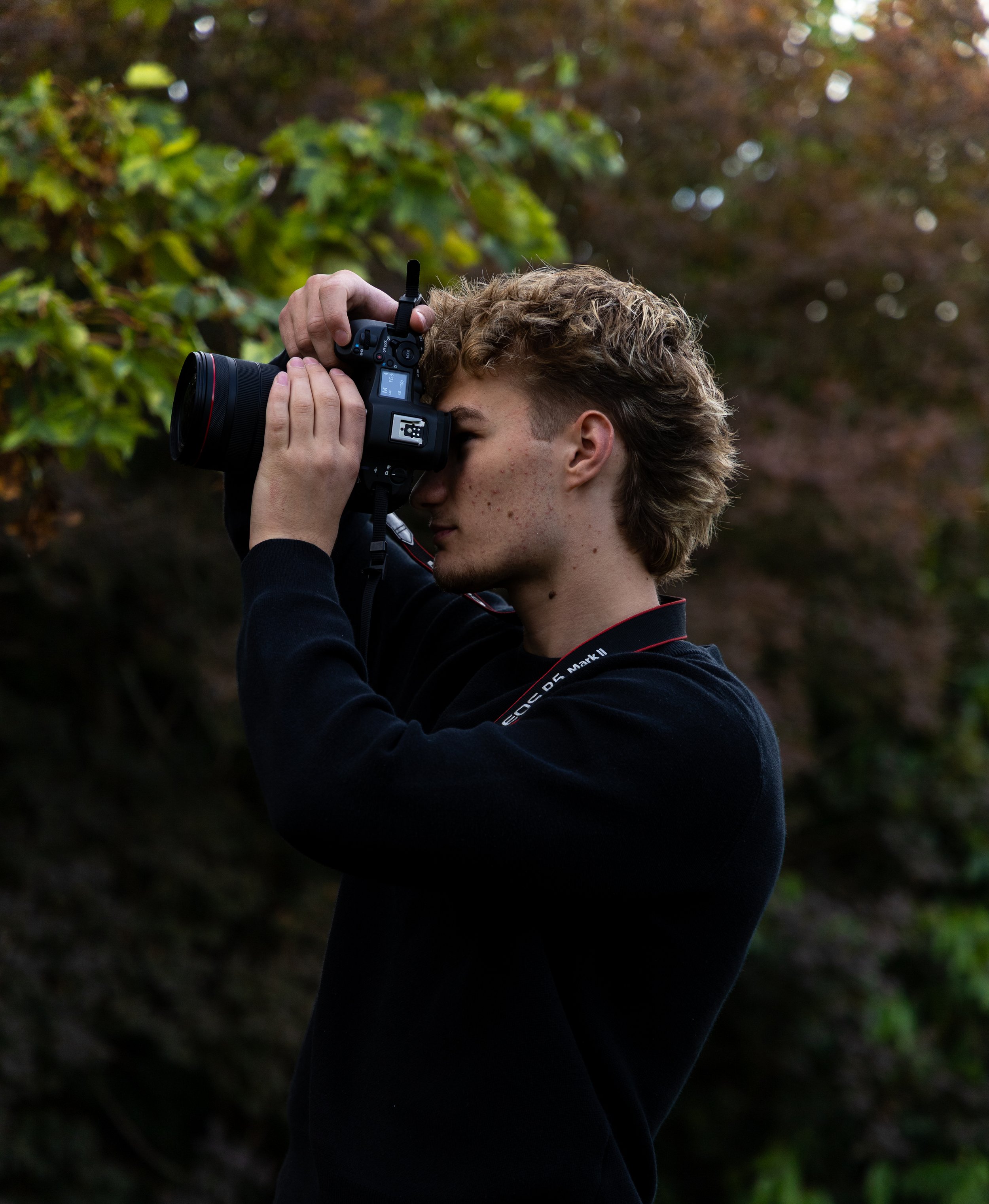 Photographer taking a close-up photo with a DSLR camera in a leafy forest