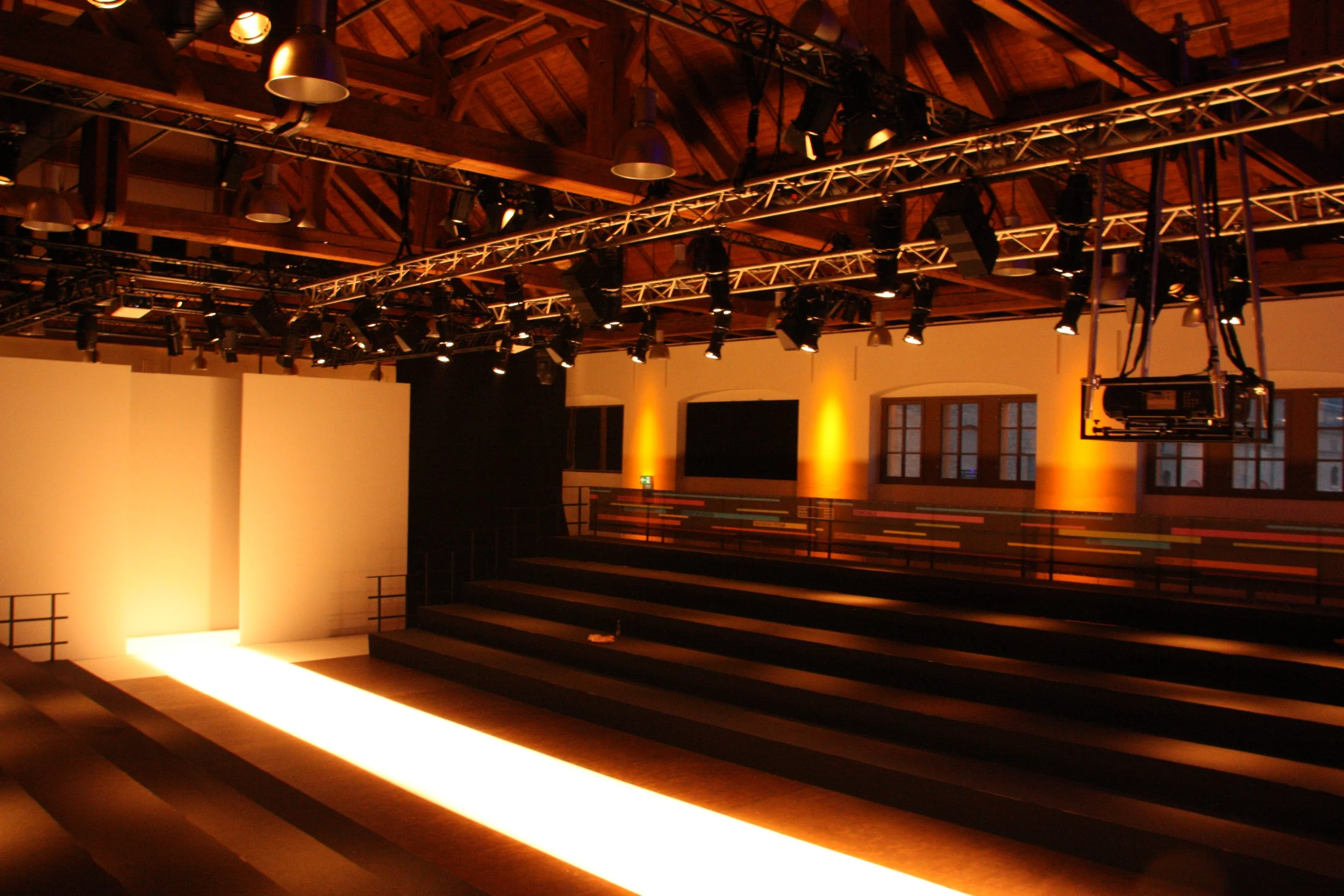 Bühnenaufbau in der Schinkelhalle Potsdam mit Tribüne, Lichttechnik und warm beleuchtetem Holzfachwerk.