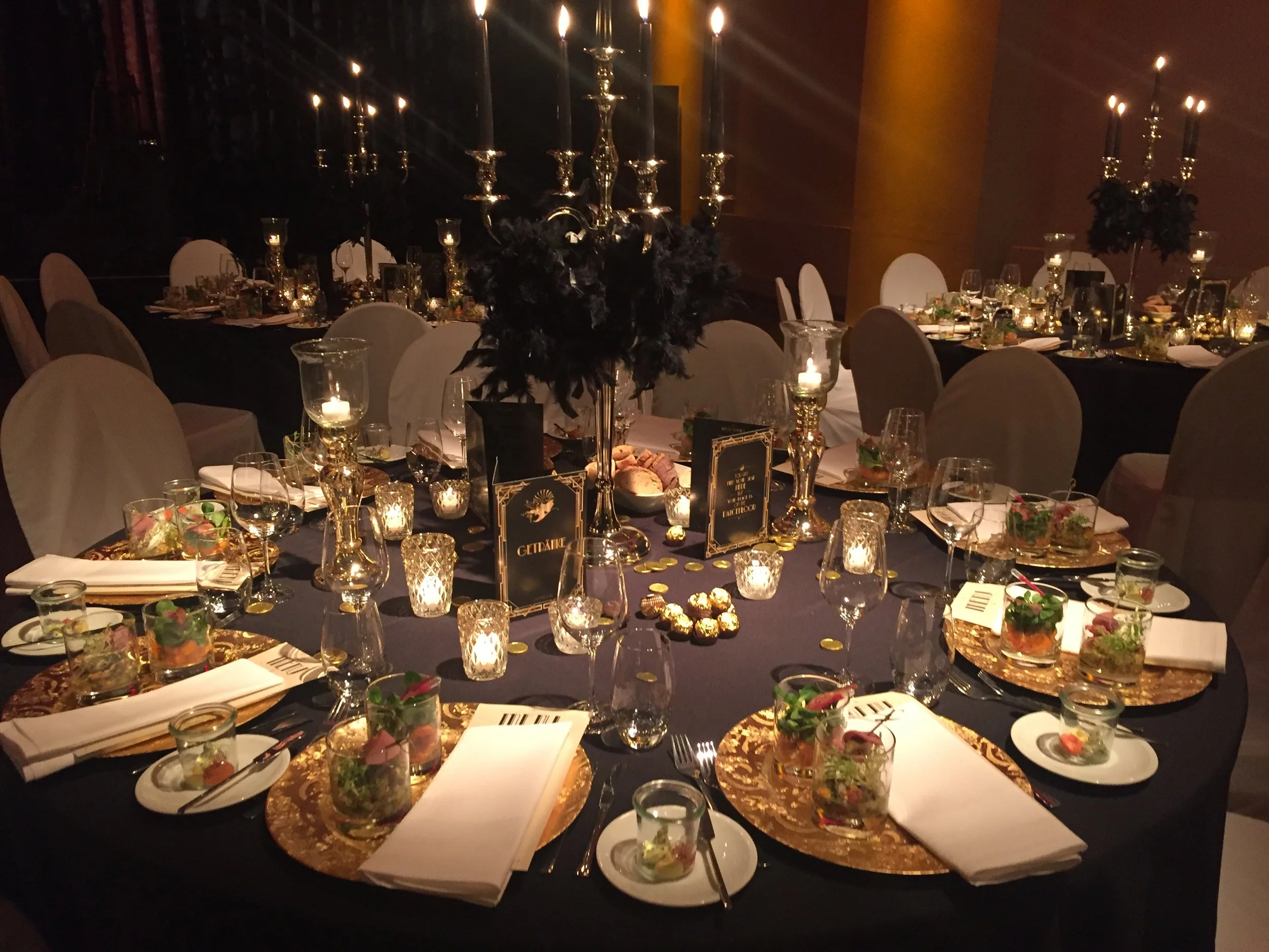 Festlich gedeckter Hochzeitstisch in der Schinkelhalle Potsdam mit Kerzen, dunkler Tischdekoration und goldenen Akzenten.