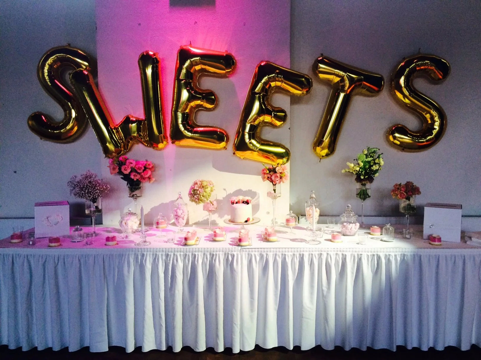 Candybar bei einer Hochzeit in der Schinkelhalle Potsdam mit floraler Dekoration und goldenen Ballonbuchstaben.