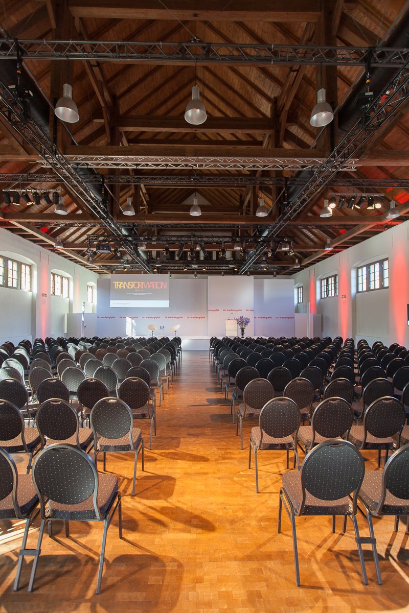 „Tagung in der Schinkelhalle Potsdam mit Bühne, Präsentationsscreen und parlamentarischer Bestuhlung.“