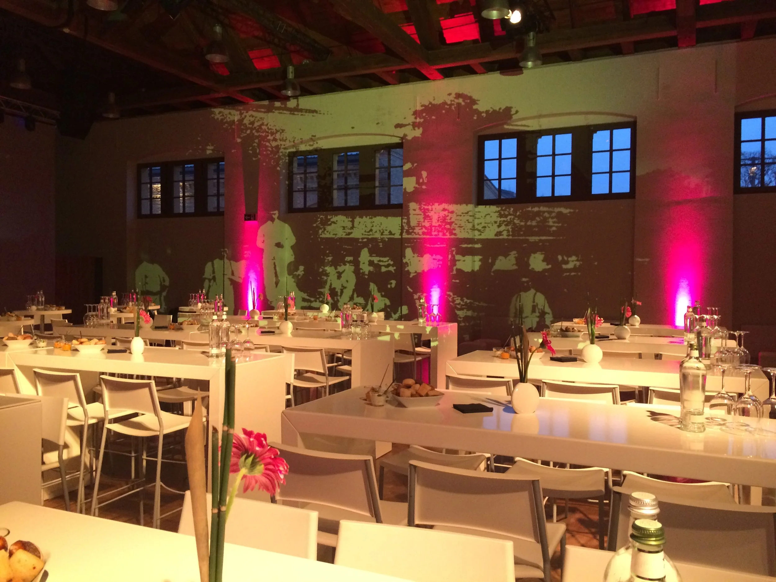 Festlich gedeckter Bankettbereich in der Schinkelhalle Potsdam mit Projektionen und floraler Dekoration.