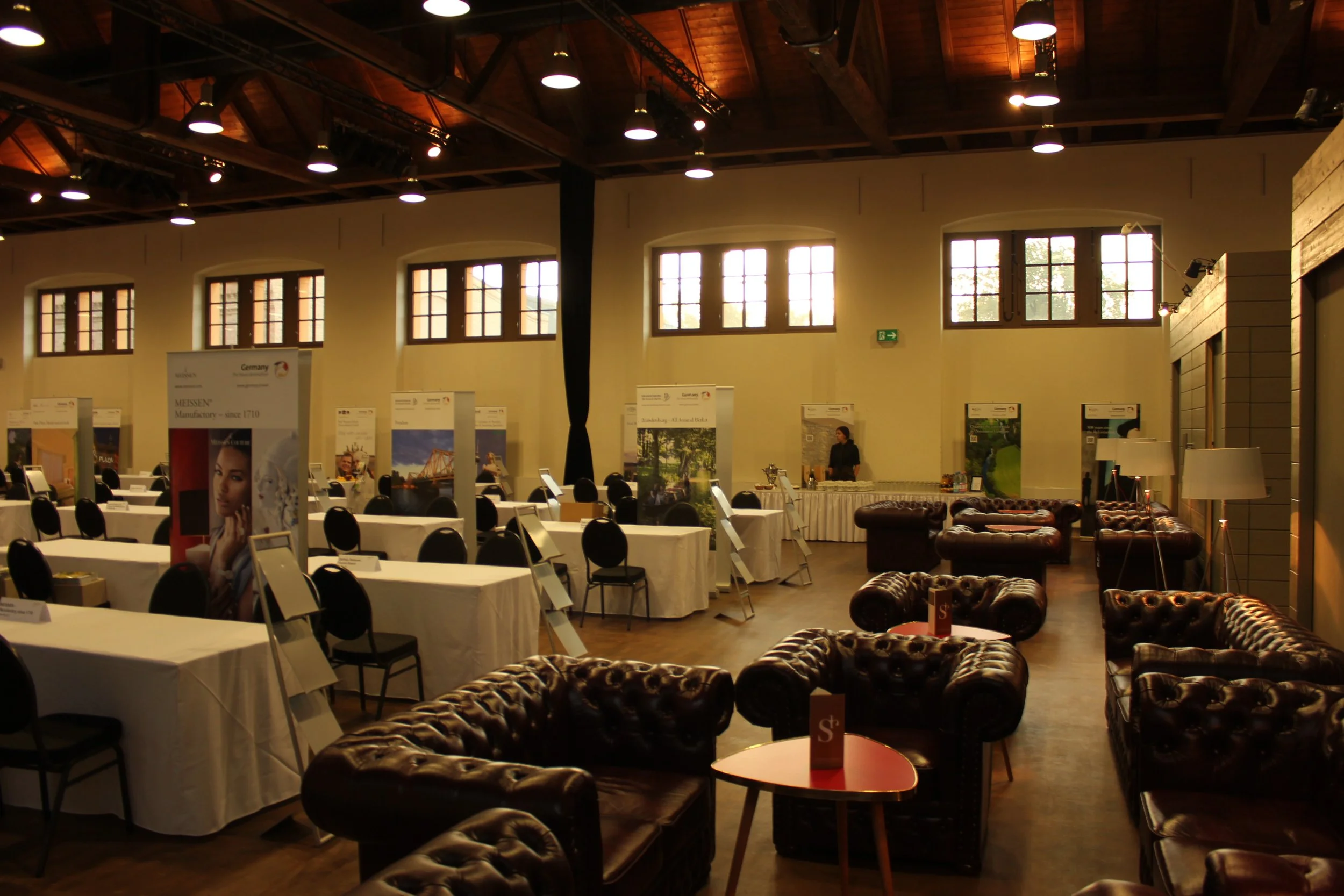 Messebereich in der Schinkelhalle Potsdam mit Informationsständen, Sitzgruppen und Aufenthaltsbereich.