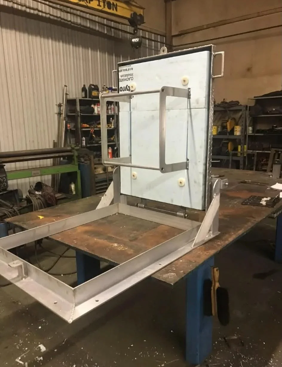A metal frame structure with a whiteboard attached, placed on a workbench in a workshop.