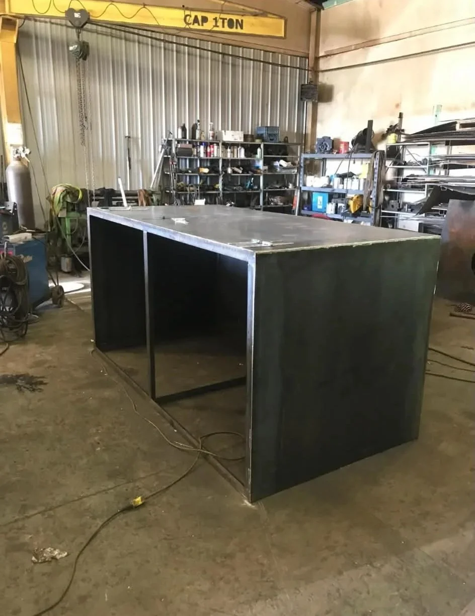 Metal work table in a workshop with shelves and tools in the background.