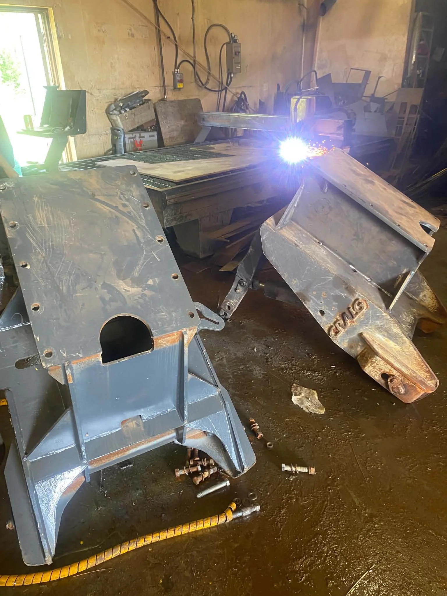 A workshop with metal parts and a welding process in action, sparks flying as metal is being welded.