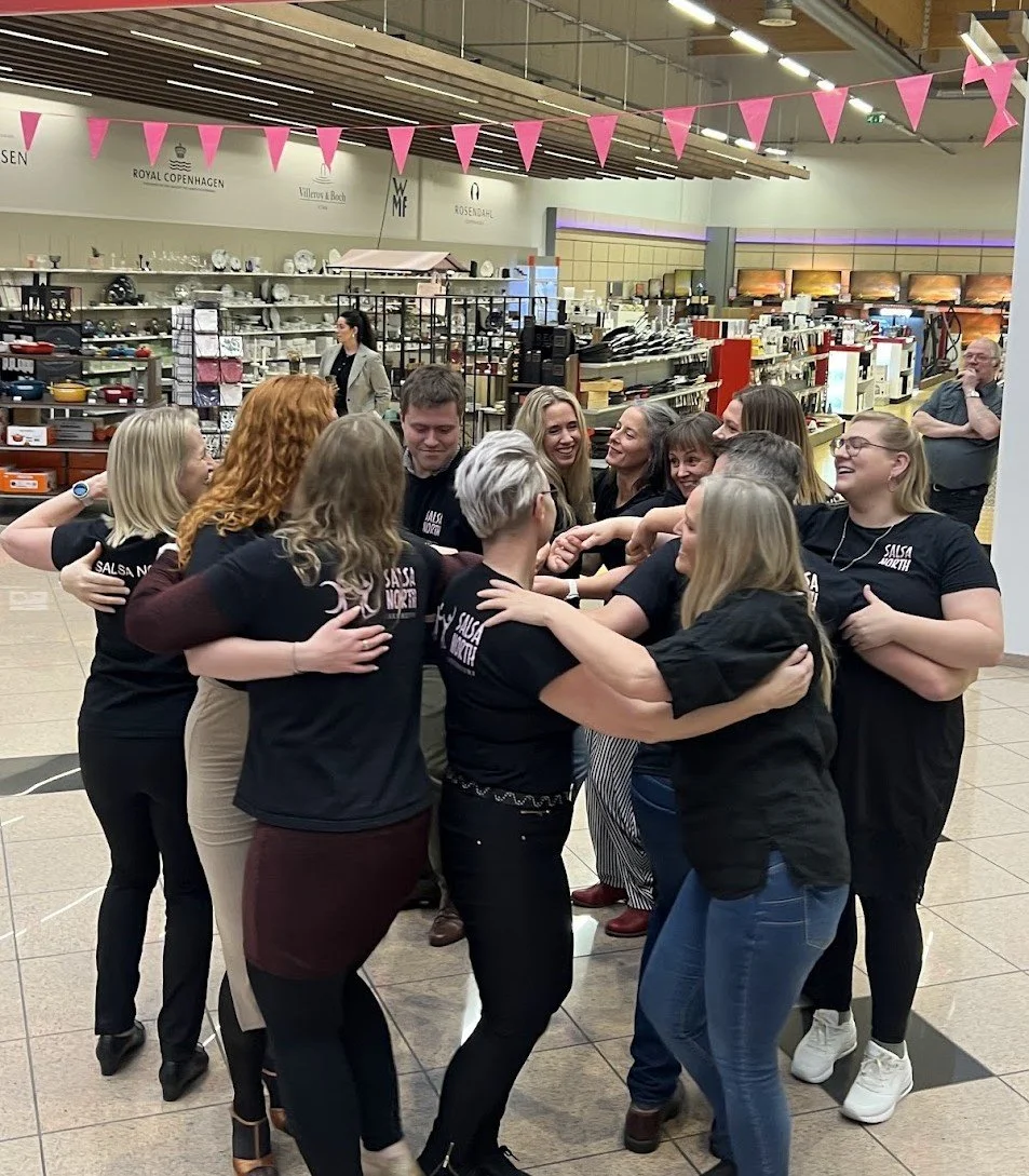 Group of women hugging and smiling in a store with pink bunting hanging overhead.