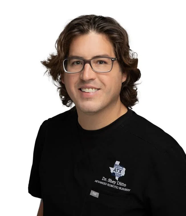 Portrait of a man with shoulder-length brown hair, glasses, wearing a black shirt with a name tag that says Dr. Shey Ditto, Advanced Robotic Surgery.
