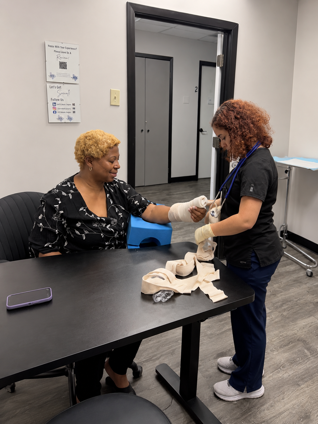 Medical professional assisting a patient with a bandaged arm at ATX Robotic Surgery.
