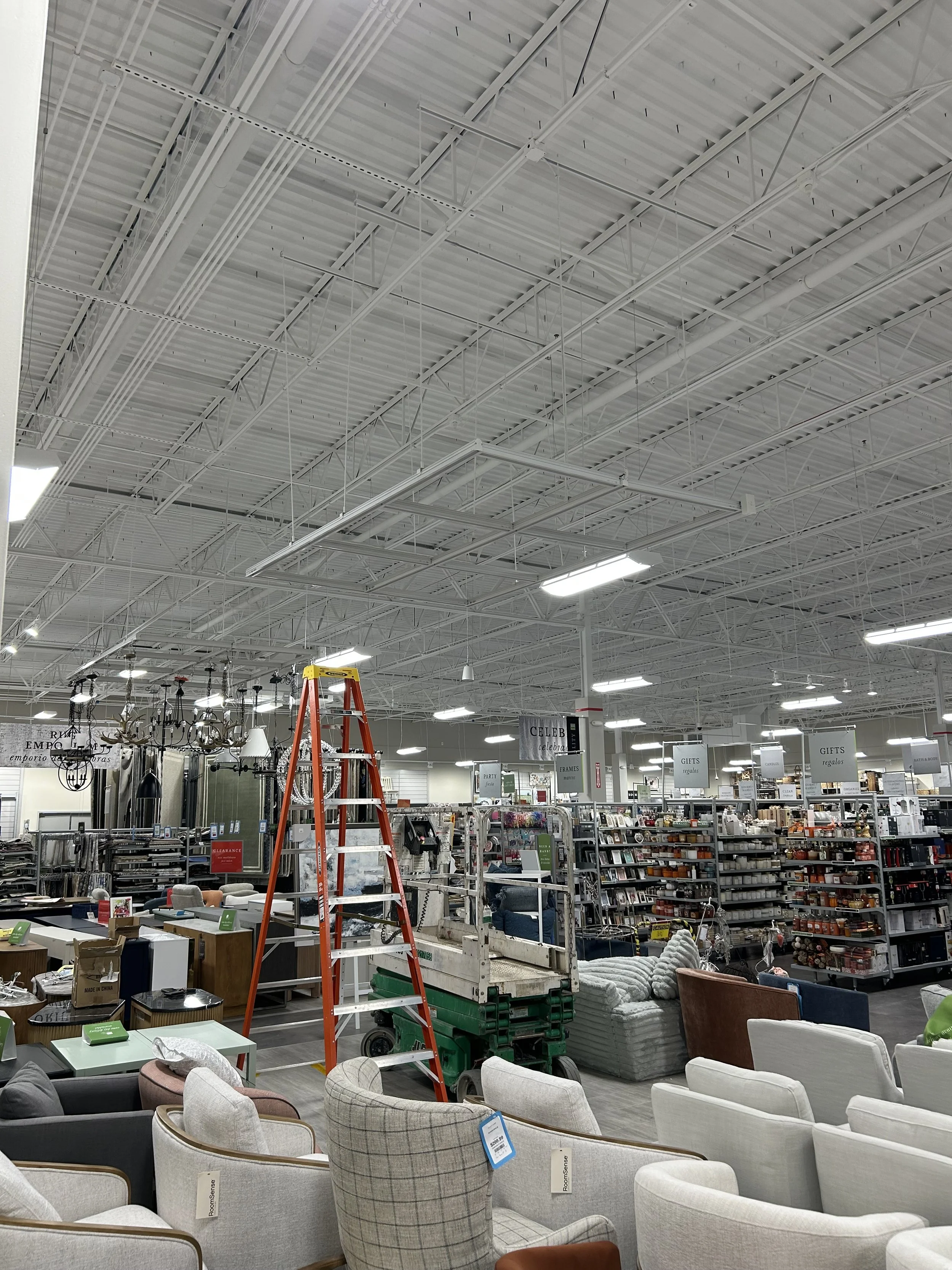 Interior of a home goods store with furniture on display, including chairs and sofas, and a red ladder to assist with store arrangements.