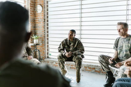 A group therapy session with diverse individuals sitting in a semi-circle in a bright room with large windows.
