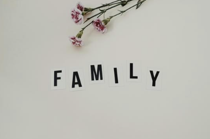 Pink carnations and the word 'FAMILY' spelled out with black and white letter tiles on a white wall.