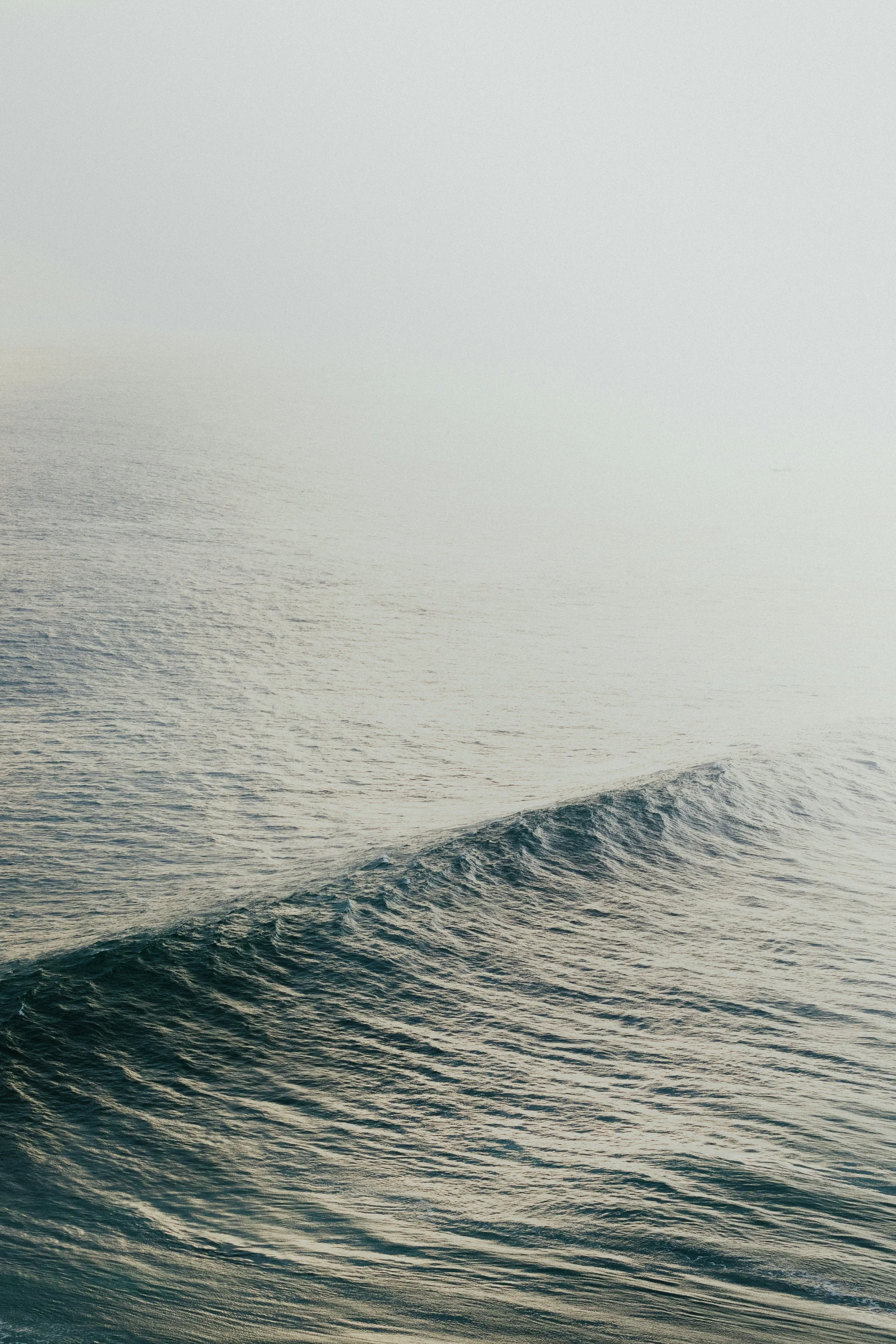 Calm ocean water with minor wave in foggy weather.
