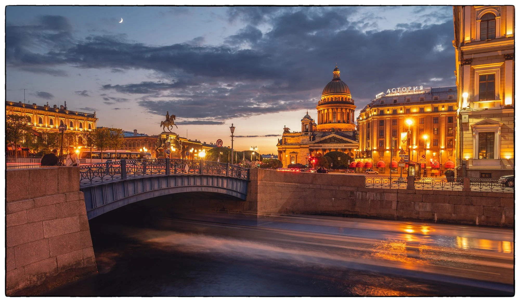 View on the Blue Bridge with the St Isaac Square and cathedral on the back just after the sunset. The lines under the bridge are what left of the moving boat that fazed out because of the long exposure I used to take this shot