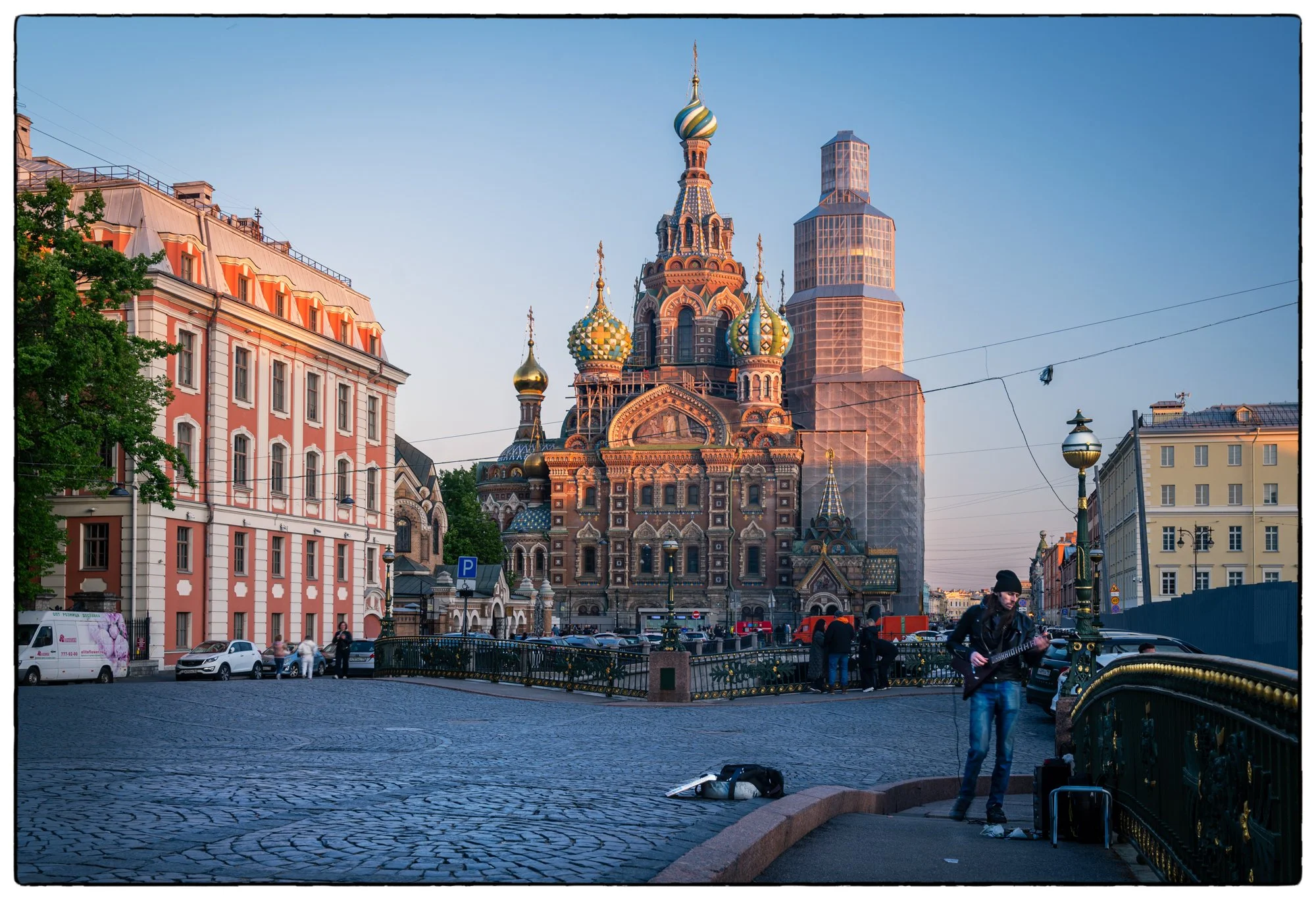 A musician plays guitar on the Malo-Konushennyy Bridge in the evening.