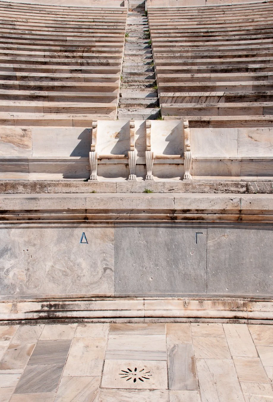 Marble stairs leading up behind two marble chairs at the original Olympic Stadium in Athens.