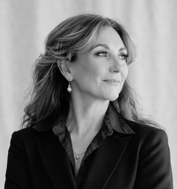 Black and white portrait of Corinne MacLellan, wearing earrings and a blazer, looking to her right.