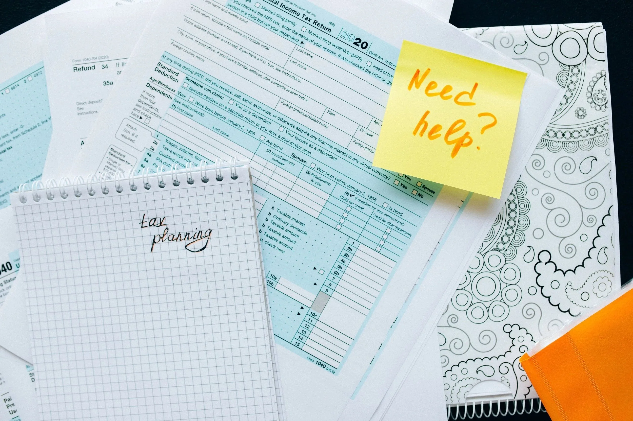Various documents including a 2020 tax return, a tax planning notebook, and a note with 'Need help?' written on it.