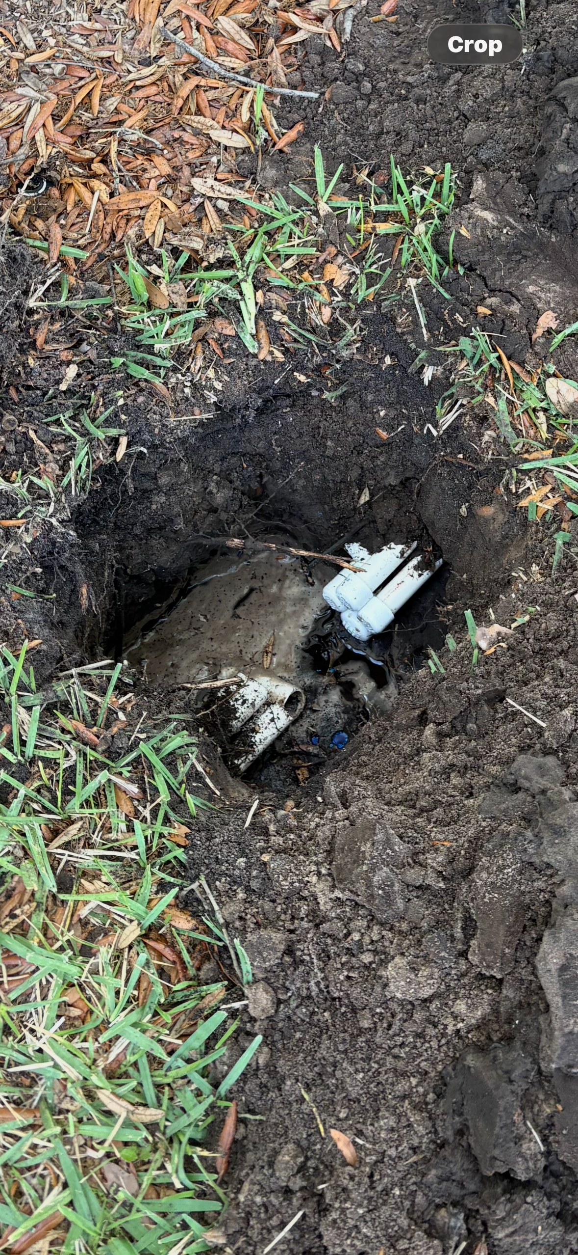 A hole in the ground with irrigation pipes that have been capped off.