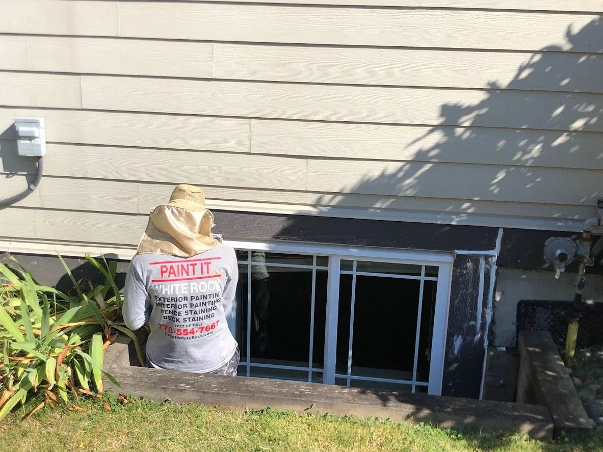 After pressure washing, we are prepping the house by scraping, sanding and caulking the holes before masking and spraying the paint!