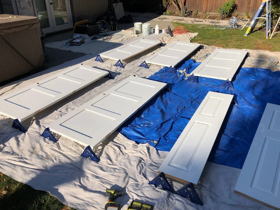 Before ... the client had just bought these new wood doors and wanted them painted, and since they hadn't hung them yet and they didn't have space to spray them inside, we tarped off their backyard and then sprayed them!