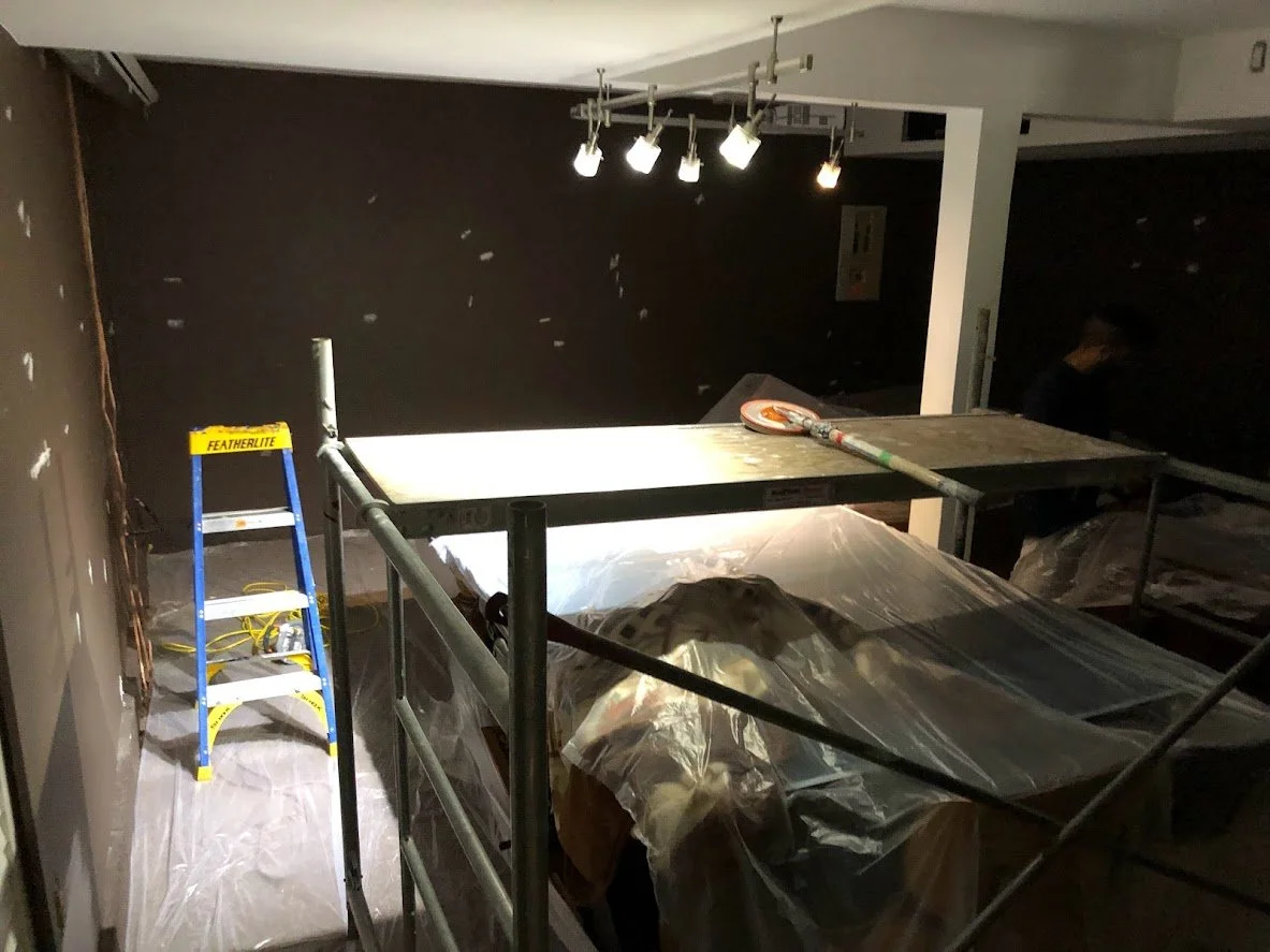 Look how dark this space looks currently.

After covering the floor we brought scaffolding in so we could paint the ceiling. The client had this very expensive ping pong table that he didn't want moved because he was worried about damage and it had b