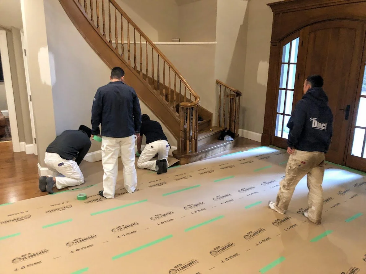 Before ... we are covering this beautiful hardwood floor before we bring scaffolding in to reach this cathedral ceiling in this entryway